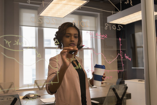 Businesswoman writing on glass wall