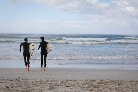Father and son with surfboard running towards sea