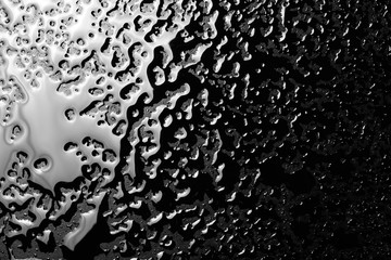Water puddle and droplets isolated on black background and texture, top view