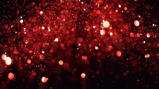 Super slow motion of glittering red particles on black background. Shallow depth of focus. Filmed on high speed cinema camera, 1000 fps.