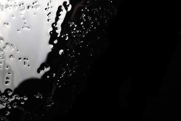 Water puddle and droplets isolated on black background and texture, top view