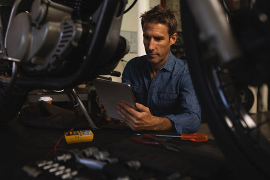 Bike mechanic using digital tablet while working in garage