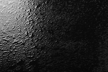 Water puddle and droplets isolated on black background and texture, top view