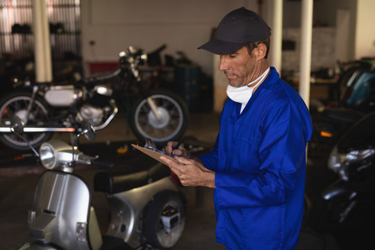 Bike mechanic maintaining automobile records on clipboard 