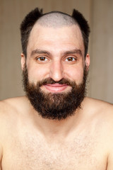 Obraz premium Portrait of happy man with an unusual hairstyle and beard with a naked torso