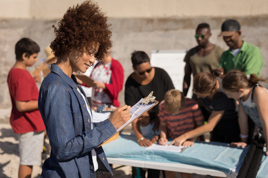 Woman writing on clipboard at beach on a sunny day
