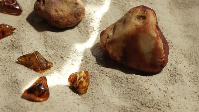 Sunbeam illumines stone and natural baltic amber against a background of sand