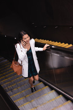 Woman talking on mobile phone on escalator
