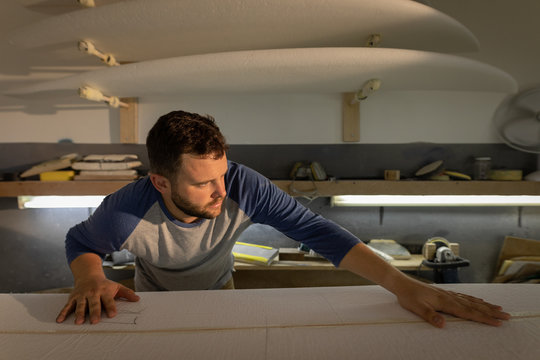 Man checking surfboard in a workshop