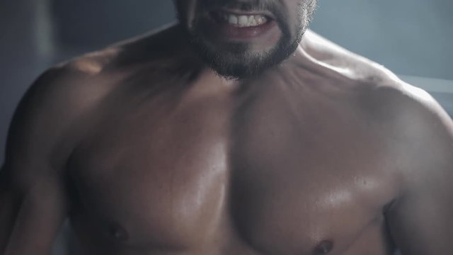 Tired male boxer standing on the boxing ring. Close up.