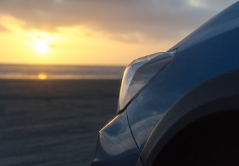 Blue hatchback under sunset  lights at sand beach