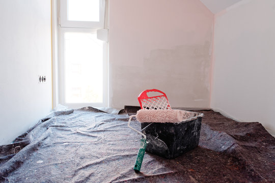 farbeimer mit farbrolle im leeren zimmer