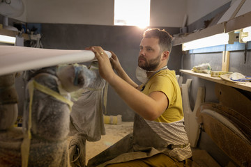 Man checking surfboard in a workshop