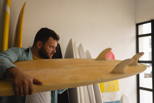 Man checking surfboard in a workshop