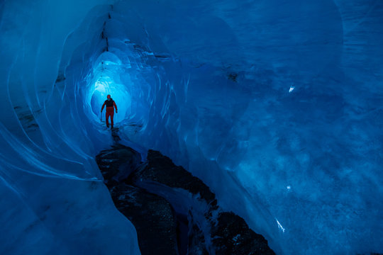 Man walking through a tunnel of an ice cave in Alaska. Glacier caves on the Matanuska Glacier in the Chugach Mountains.