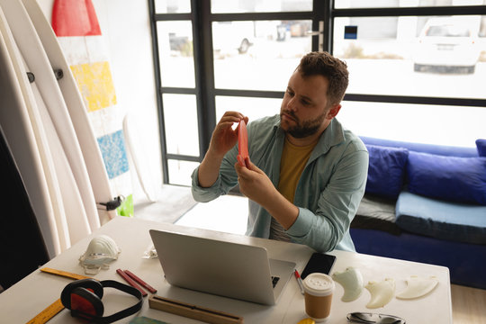 Man examining surfboard fin in a workshop