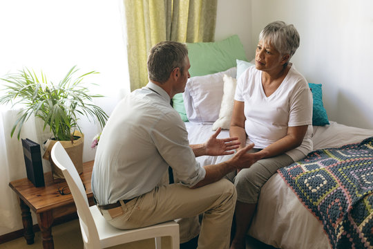 Male doctor interacting with senior female patient at retirement home