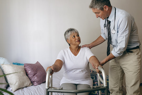 Male doctor helping senior female patient to walk with walker