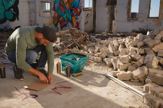 Graffiti artist drawing on card board wit marker on street side 