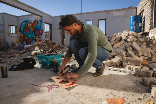 Graffiti artist  spray painting on card board at alley