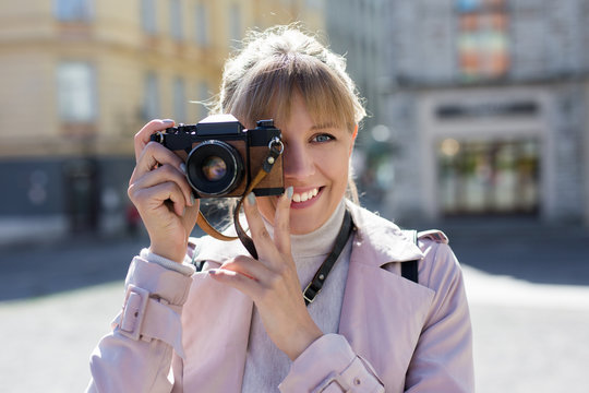 photography, tourism and travel concept - woman taking photos with vintage camera