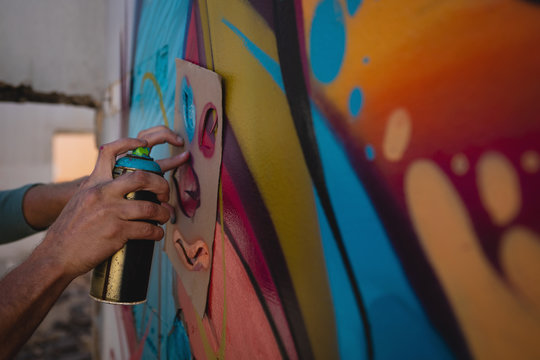 Graffiti artist  spray painting on card board at alley