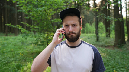 portrait of stylish hipster guy talk with friend via mobile smart phone while strolling...