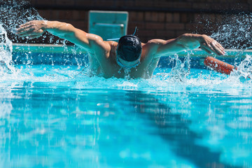 Young male swimmer with swim goggle swimming at swimming pool 