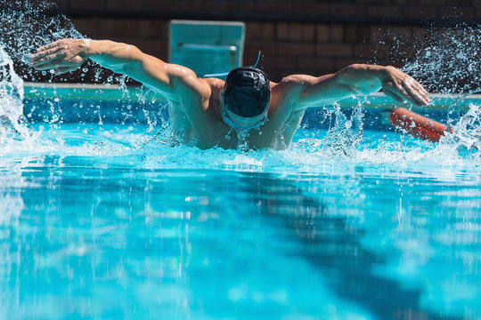 Young male swimmer with swim goggle swimming at swimming pool 