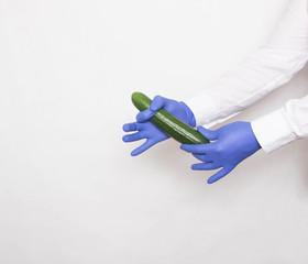The doctor in medical gloves holds a cucumber in his hands, the concept of increasing the penis...