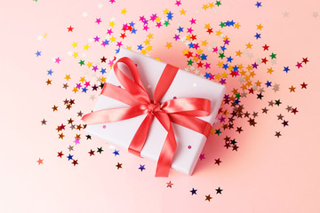 Gift box with ribbon on pink background close-up, top view