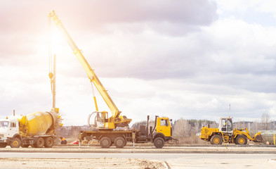 Construction of a new road and installation of lampposts using a truck crane and cement truck, workers, copy space, profession, loader, industry