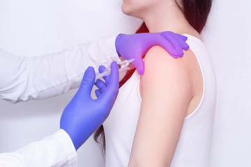 Doctor makes an injection of blockade of chondroprotector and anti-inflammatory drug in the girl's sore shoulder, white background, close-up, ozone therapy - obrazy, fototapety, plakaty