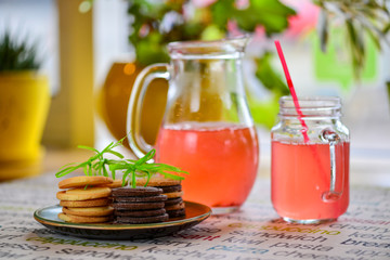 a jug with a campot and a glass with a straw and a cookie