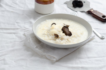 Risotto with black truffle and parmesan cheese  on white linen tablecloth, Copyspace.
