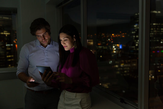 Young multi-ethnic office executives working and discussing over digital tablet near window in a mod