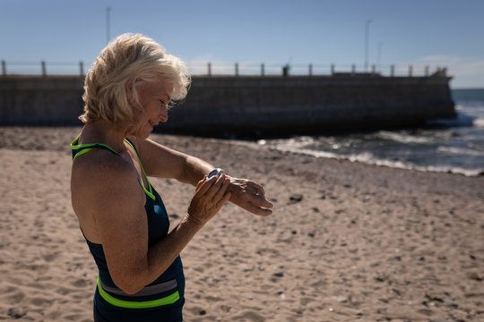 Active senior woman using smartwatch on the beach
