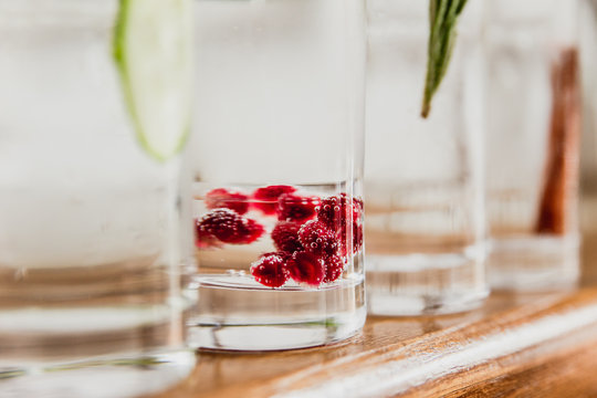 A horizontal image of 4 different refreshing gin and tonics in highball glasses. Cucumber and melon, pomegranate and basil, rosemary and apple, cinnamon and rose pepper. Selective focus.