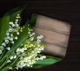 Beautiful Lily of the valley flowers on a dark textured background with a sign for the inscription Flat lay, top view