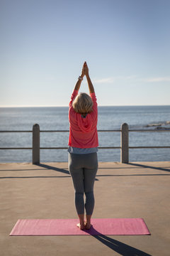 Active senior woman performing yoga on a promenade