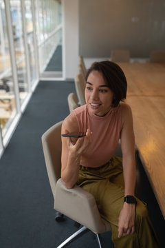 Businesswoman talking on mobile phone while sitting in the office