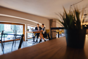 young businessmen boy and girl work with a laptop, a tablet and notes in the cafe