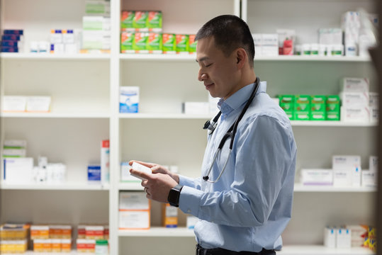 Young asian male doctor holding medicine and standing in clinic