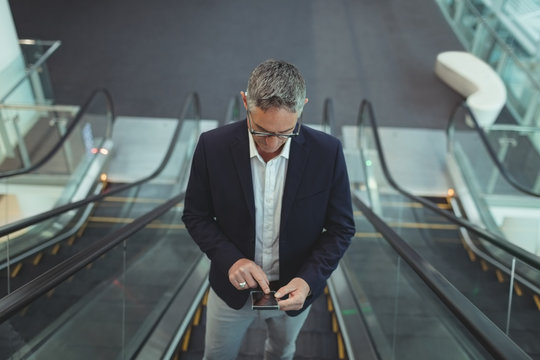 Businessman using his mobile phone on the escalator