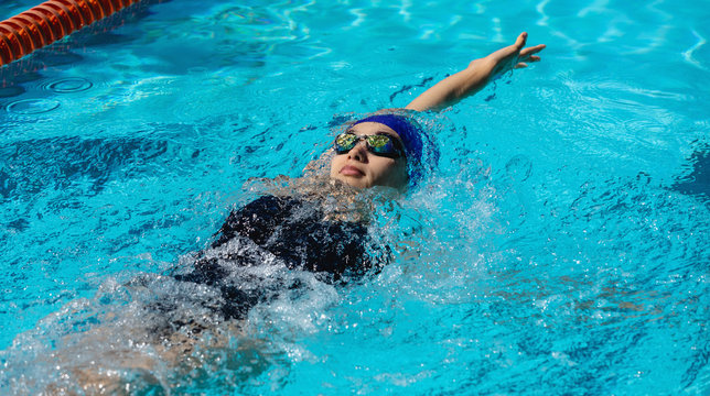 Female swimmer swimming backstroke in swimming pool