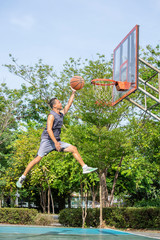 Basketball in hand man jumping Throw a basketball hoop Background  tree in park.