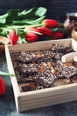 Holiday mood. Dark  handmade chocolate with nuts, coffee and red tulips