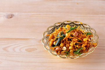 South indian spicy crunchy mix Nimco or Namkeen with peanut, rice, curry leaves and spice golden bowl background isolated.