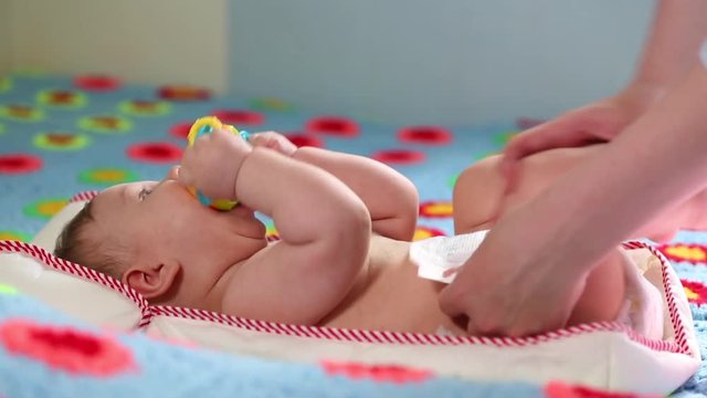 The mother changes the diaper for her newborn baby in the nursery. Newborn care, diaper change, healthy baby.