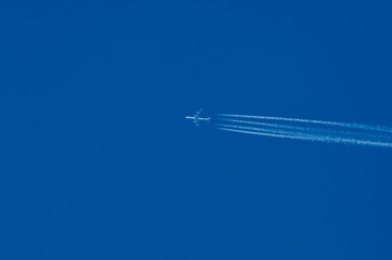 jet plane high in the blue sky with a contrail